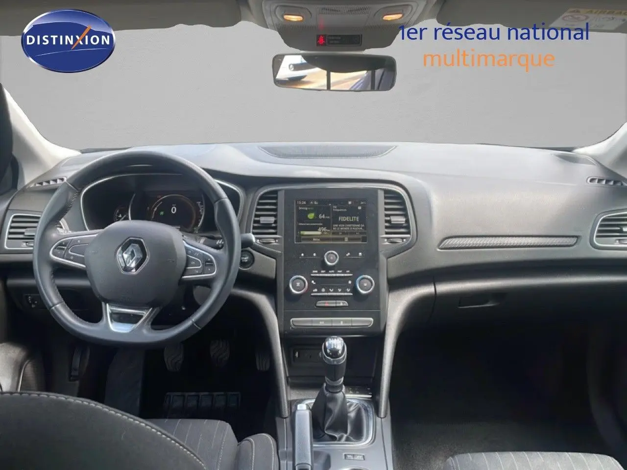 Vue intérieure avant de la Renault Mégane gris titanium, tableau de bord avec écran central et levier de vitesses manuel.