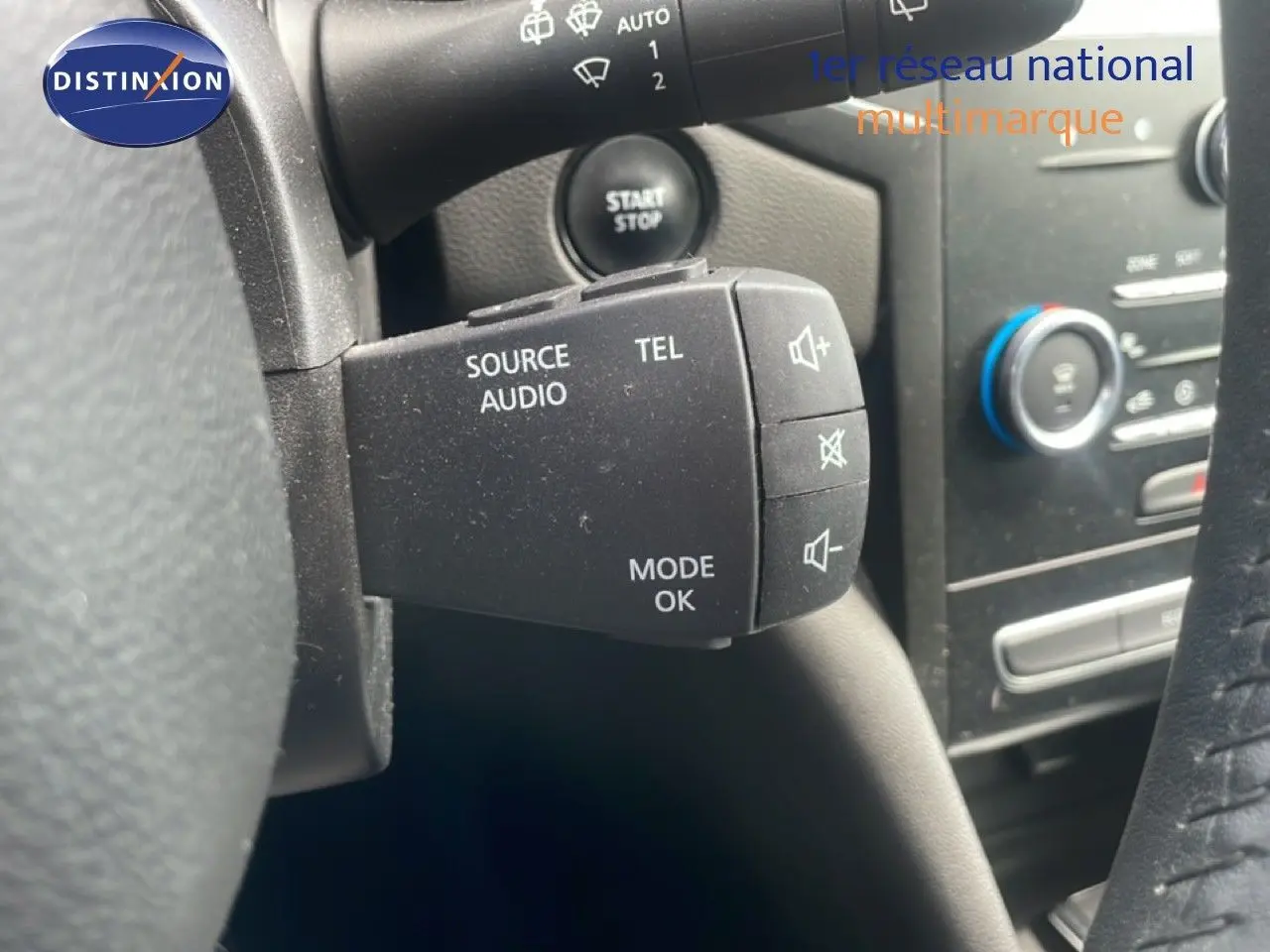 Gros plan sur la commande audio au volant d’une Renault Mégane gris titanium, avec démarrage sans clé visible.
