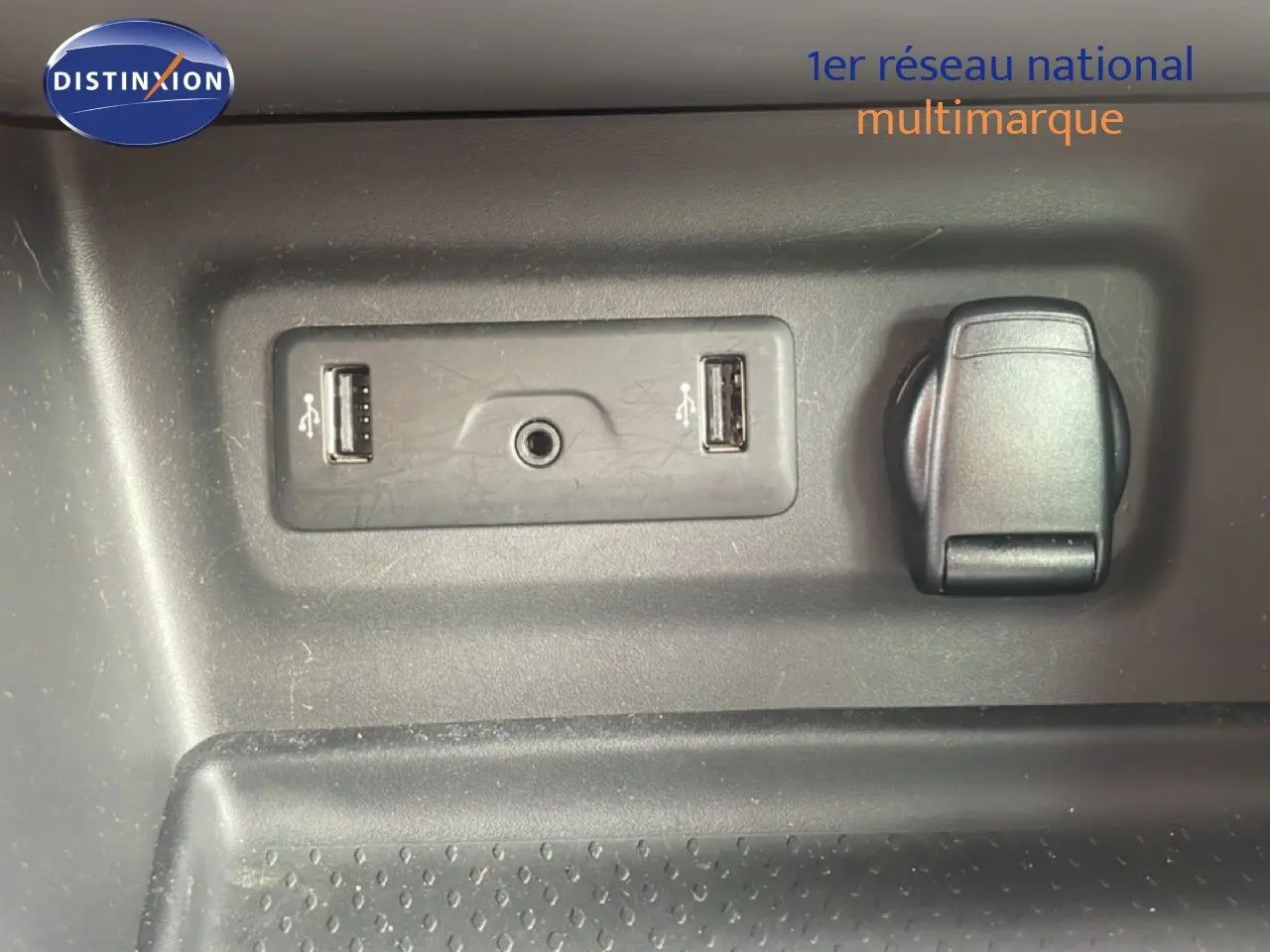 Détail intérieur montrant deux ports USB, une prise jack et une prise 12V sur fond plastique gris.