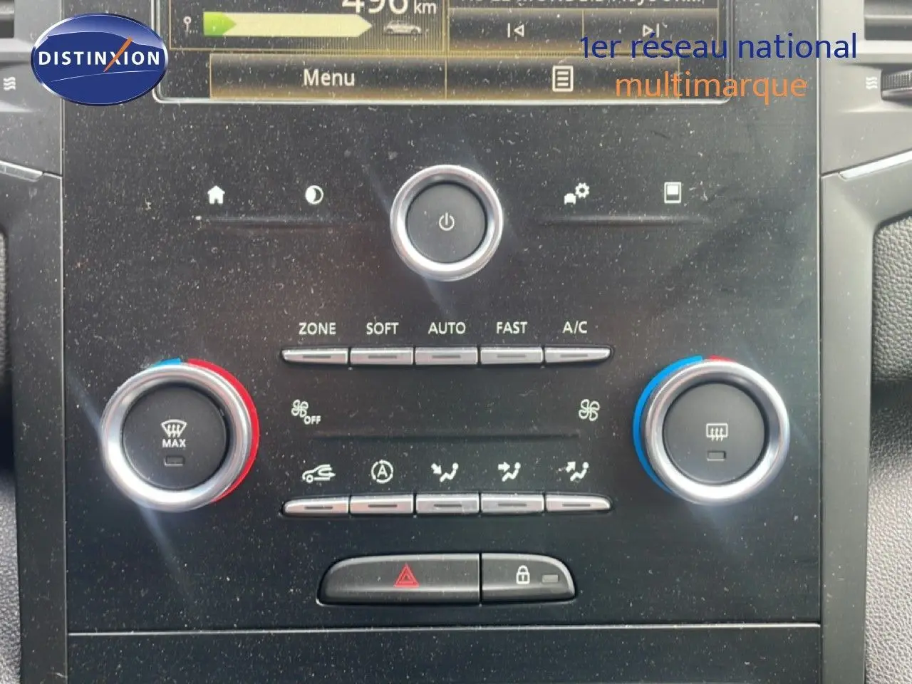 Vue rapprochée de la console centrale de la Renault Mégane gris titanium, montrant les commandes de climatisation et l’écran multimédia.
