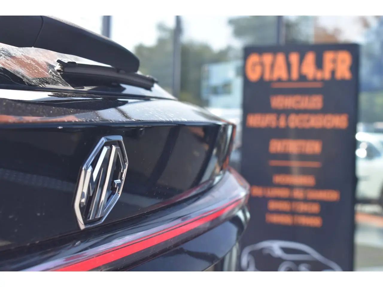 Gros plan sur l'arrière noir brillant du MG EHS 1.5 Hybrid+ avec logo MG et bande lumineuse rouge intégrée.