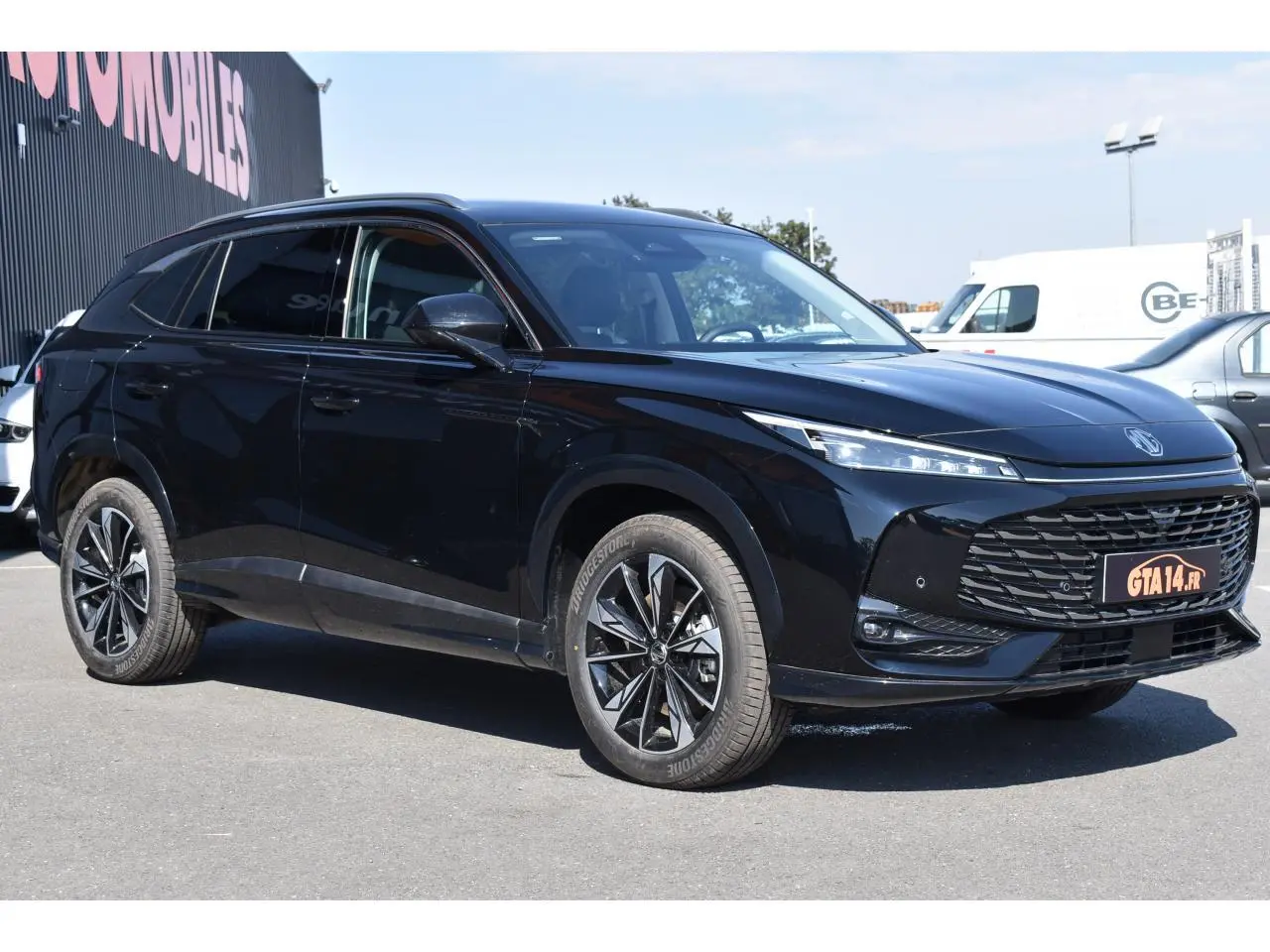 MG Motor EHS 1.5 Hybrid+ 224 ch Luxury noir, vue 3/4 avant droit avec jantes alliage 19 pouces et vitres surteintées.