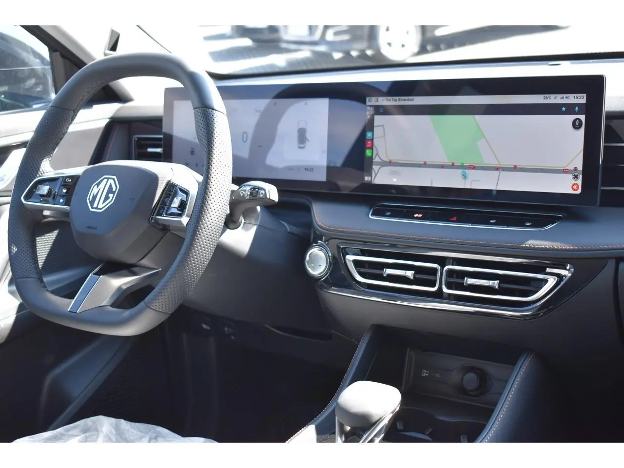 Vue intérieure côté conducteur du tableau de bord noir du MG MOTOR EHS avec écran tactile panoramique et volant multifonction.