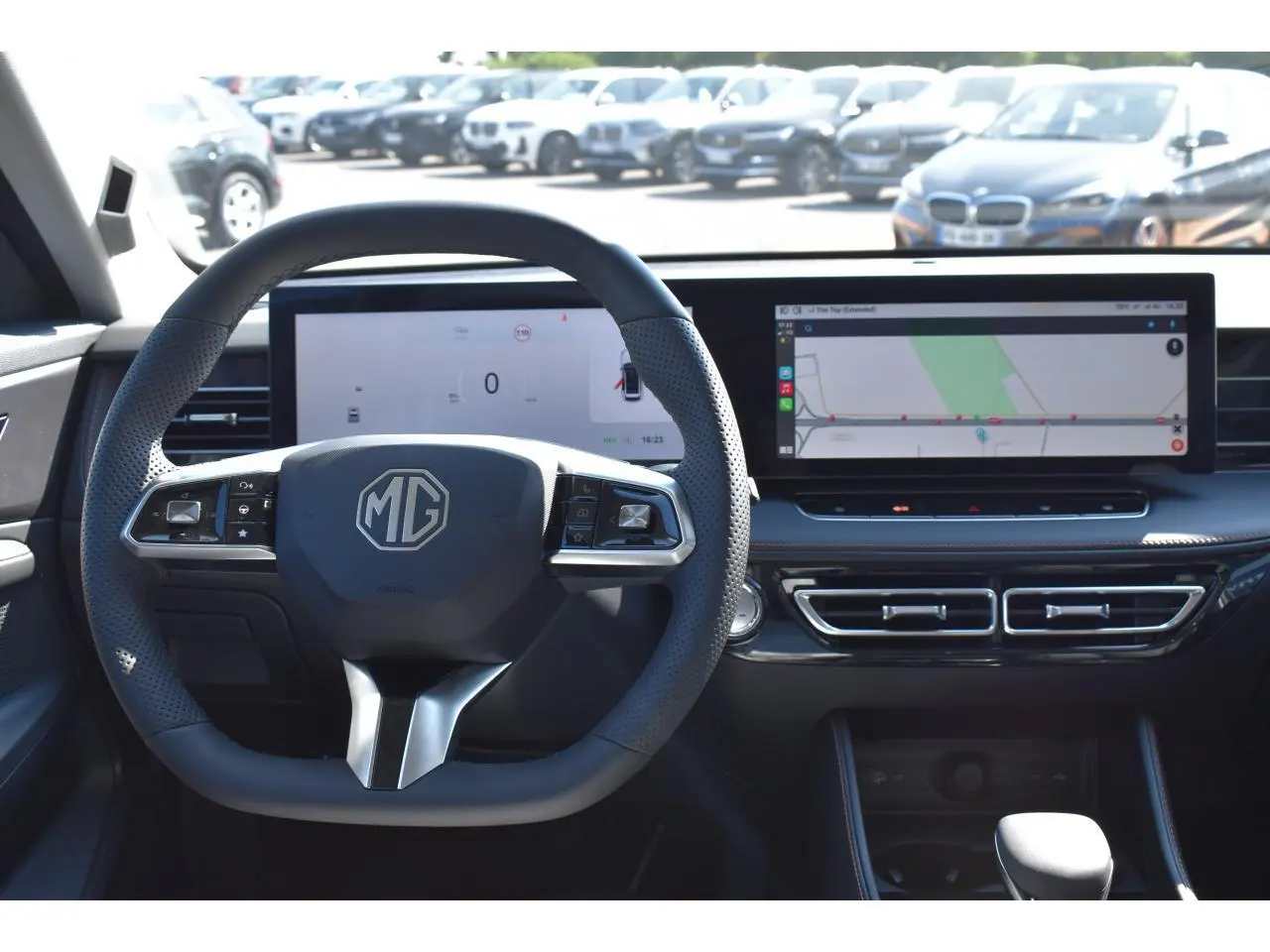 Vue intérieure centrée sur le volant noir MG avec tableau de bord numérique et écran tactile large affichant la navigation.