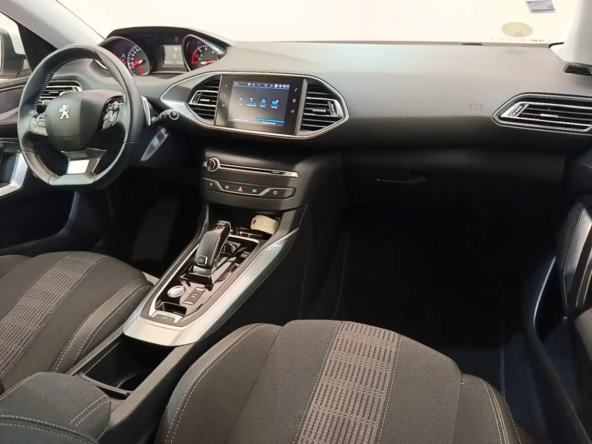 Vue intérieure côté conducteur de la Peugeot 308 2020 avec tableau de bord noir et écran tactile central lumineux.