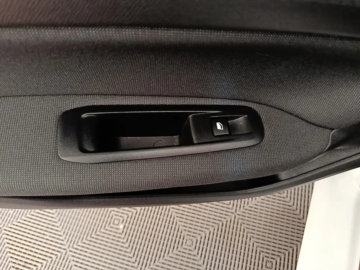 Poignée intérieure de porte côté conducteur d'une Peugeot 308 blanche, avec bouton de verrouillage intégré.