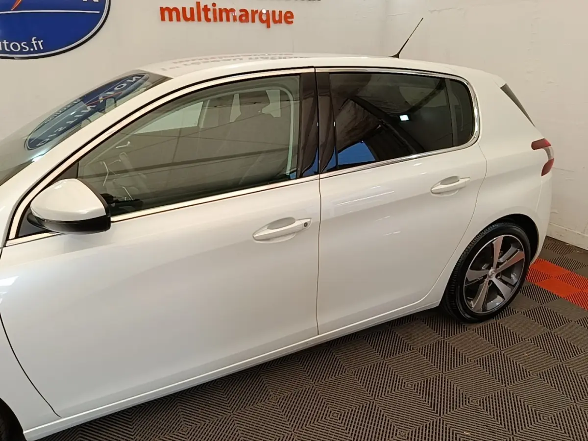 Profil côté gauche d'une Peugeot 308 blanche de 2020, avec jantes alliage et vitres teintées visibles.
