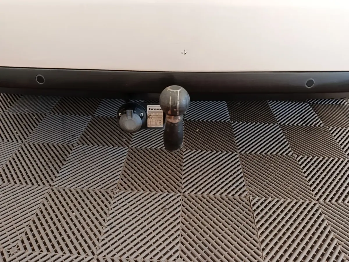 Gros plan sur l'attelage noir fixé à l'arrière d'une Peugeot 308 blanche, avec prise électrique visible à gauche.