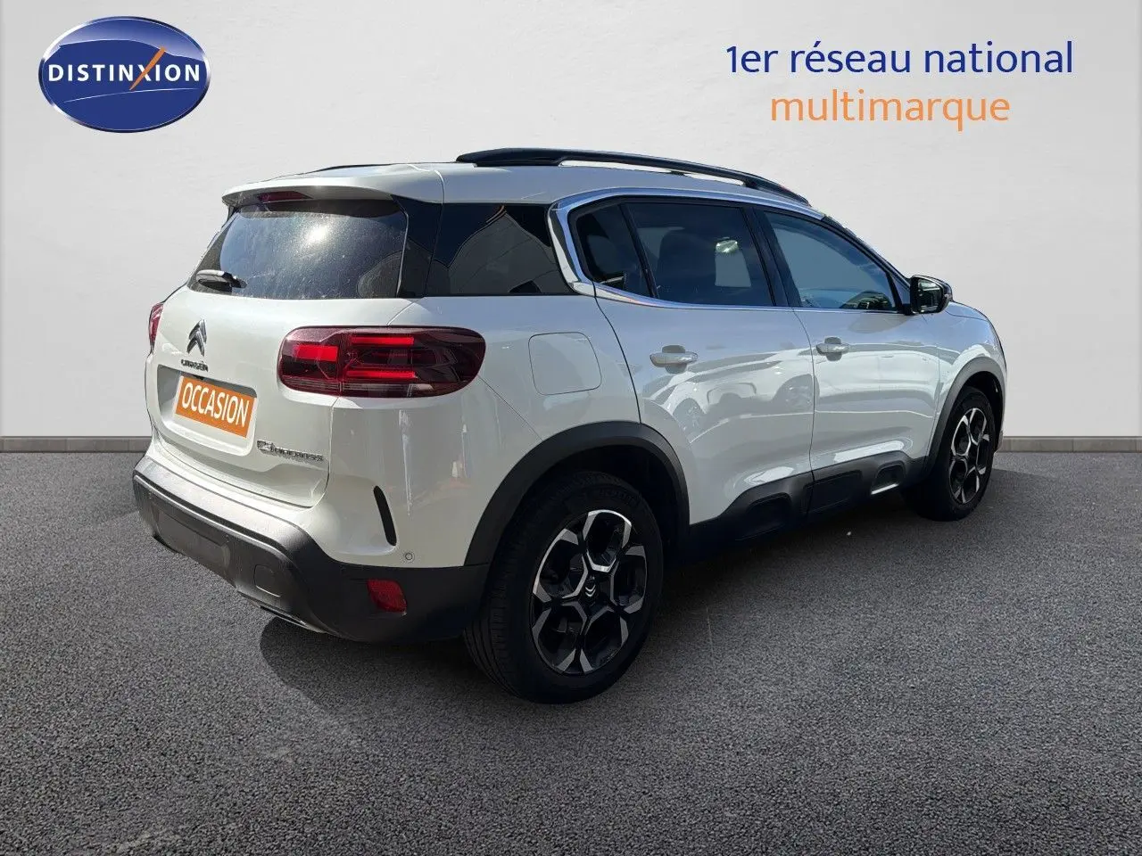 Vue 3/4 arrière droite d'un Citroën C5 Aircross blanc nacré avec toit noir et jantes noires distinctives.