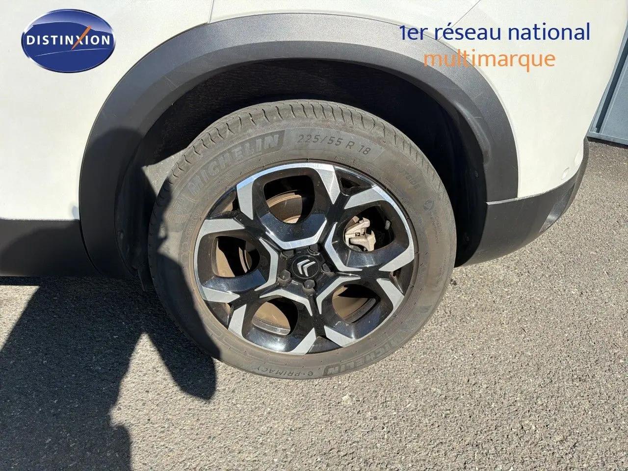 Gros plan sur la roue avant droite du Citroën C5 Aircross blanc nacré avec jante alliage noire et argentée.