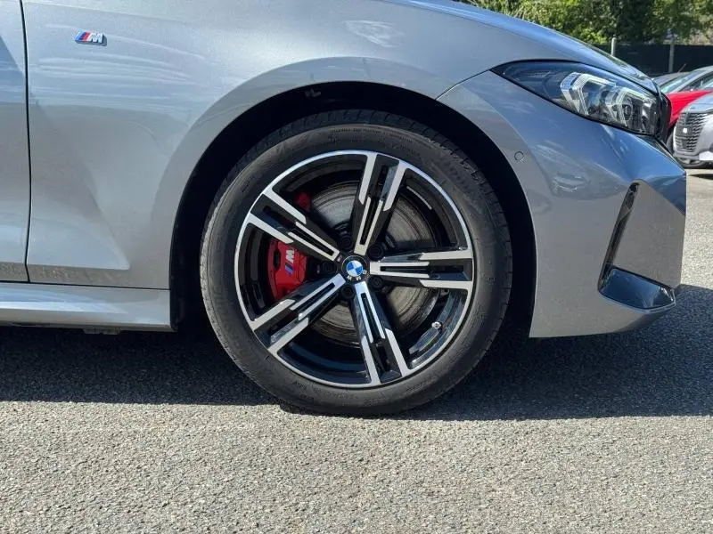 Gros plan sur la roue avant droite d'une BMW Série 3 320dA xDrive M Sport 2025 en Skyscrapergrau métallisé avec étrier de frein rouge M.