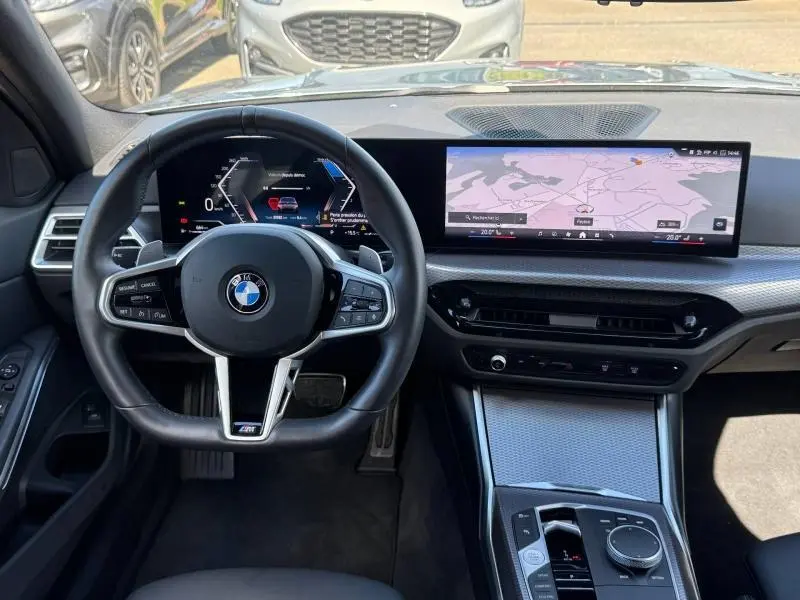Vue intérieure frontale du poste de conduite de la BMW Série 3 320dA xDrive M Sport avec écran large et volant M Sport noir.
