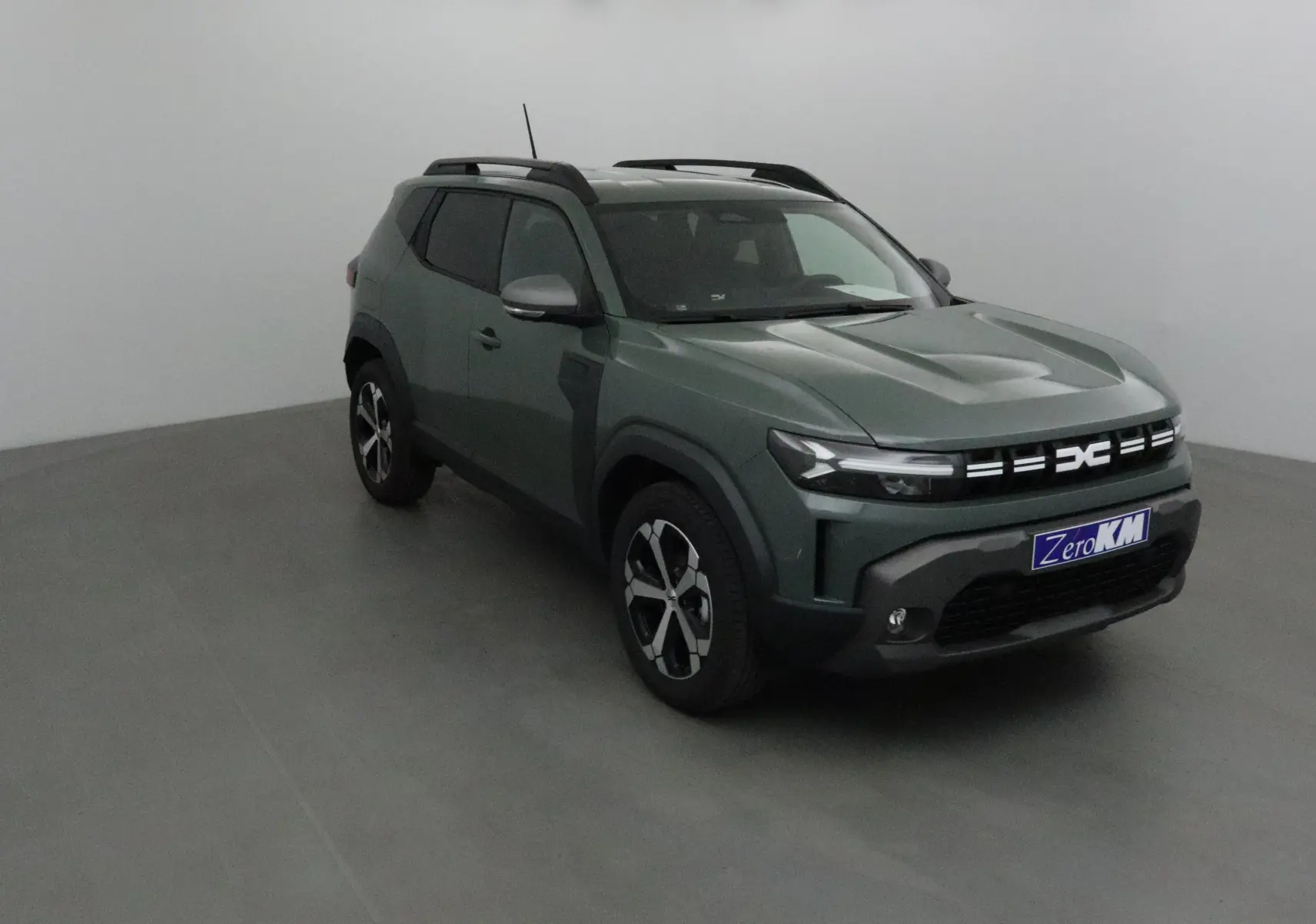 Vue 3/4 avant droit d'un Dacia Duster 2025 kaki lichen avec calandre moderne et jantes alliage noires.
