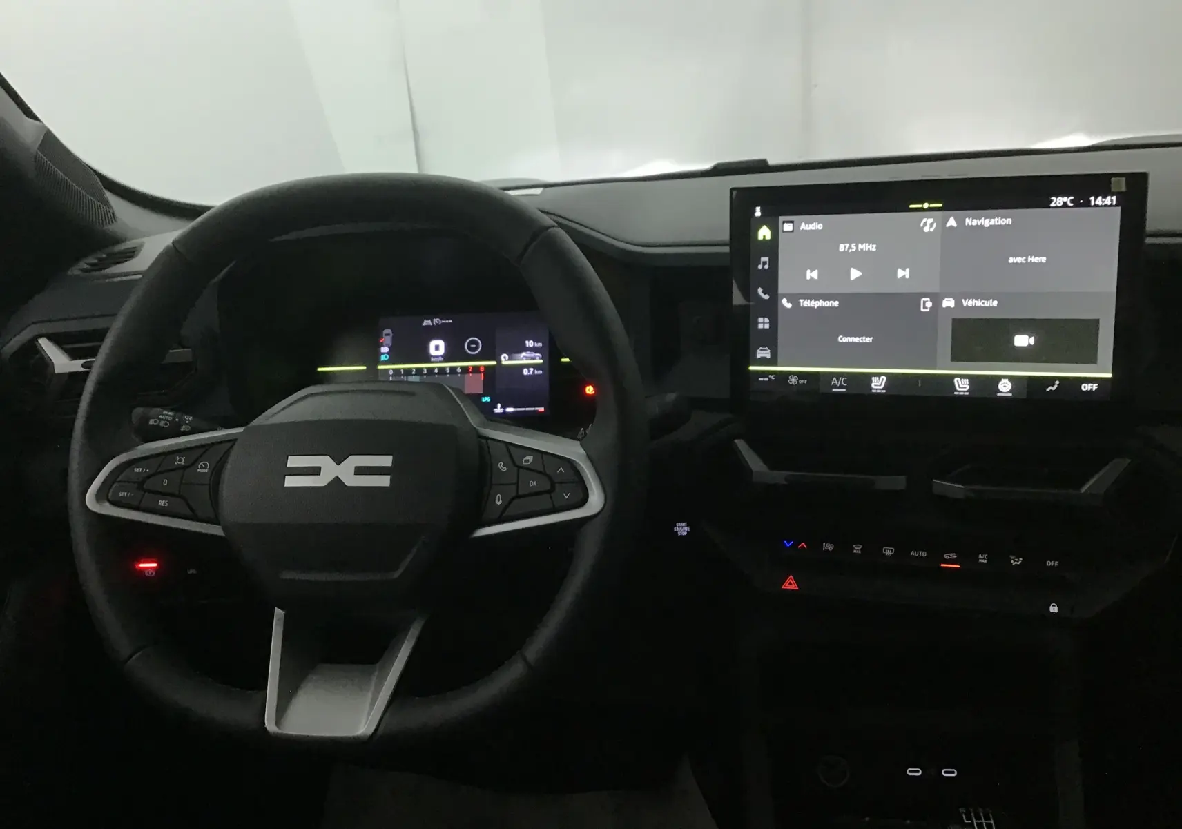 Vue intérieure centrée sur le volant multifonction et l'écran tactile du tableau de bord du Dacia Duster 2025.