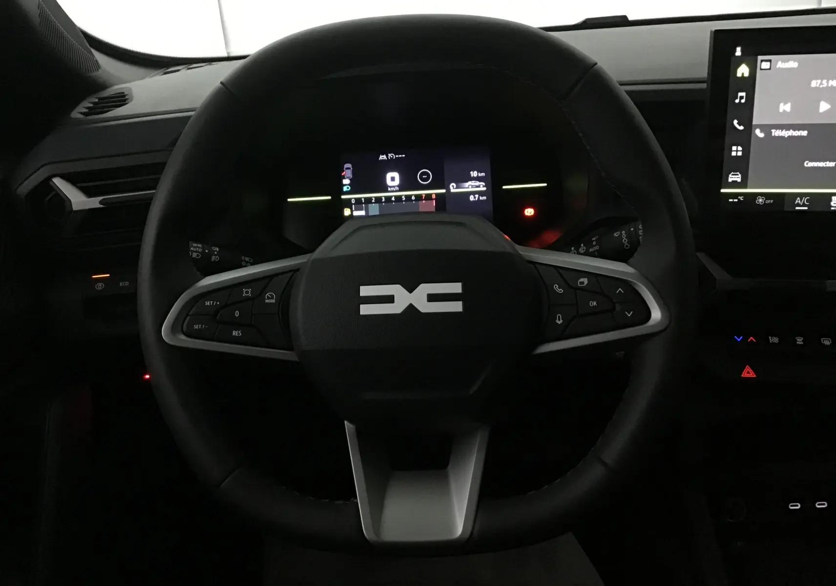 Vue rapprochée du volant noir du Dacia Duster 2025 avec tableau de bord numérique et écran tactile central.