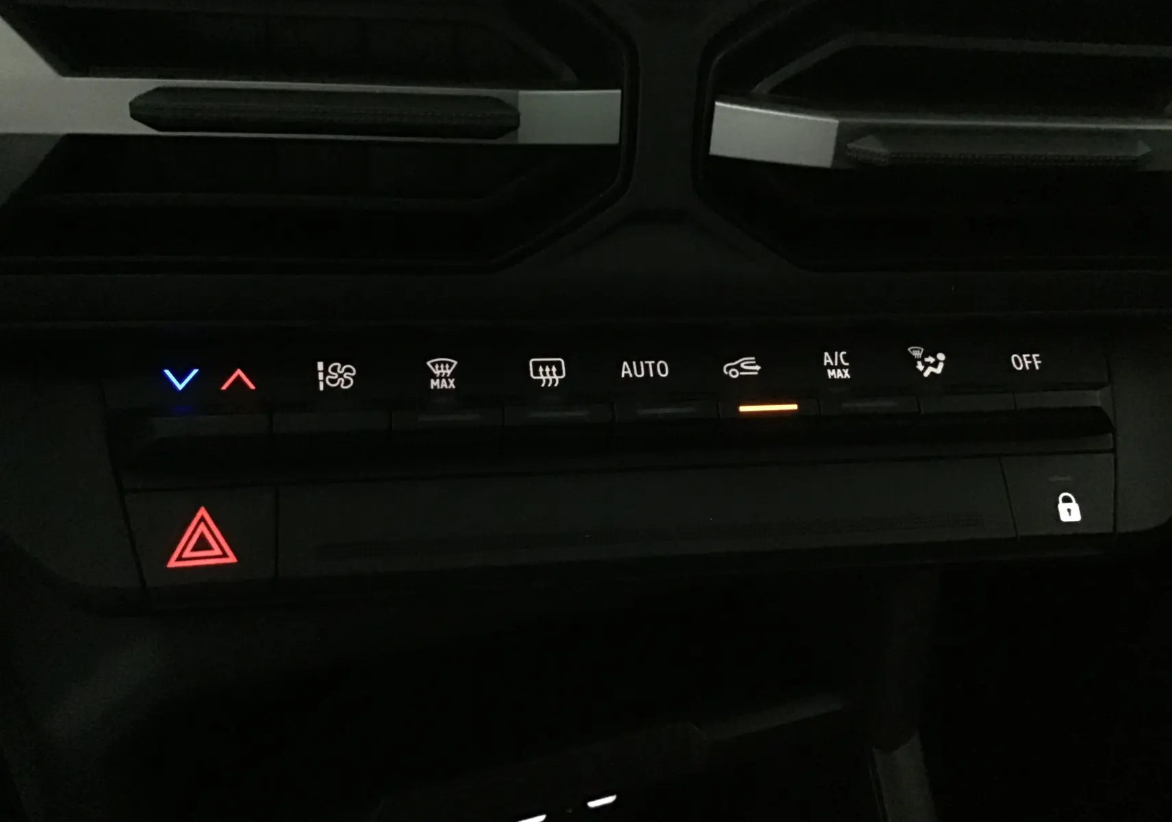 Panneau de commandes climatisation et sécurité du Dacia Duster 2025, avec voyants lumineux rouges, bleus et orange.