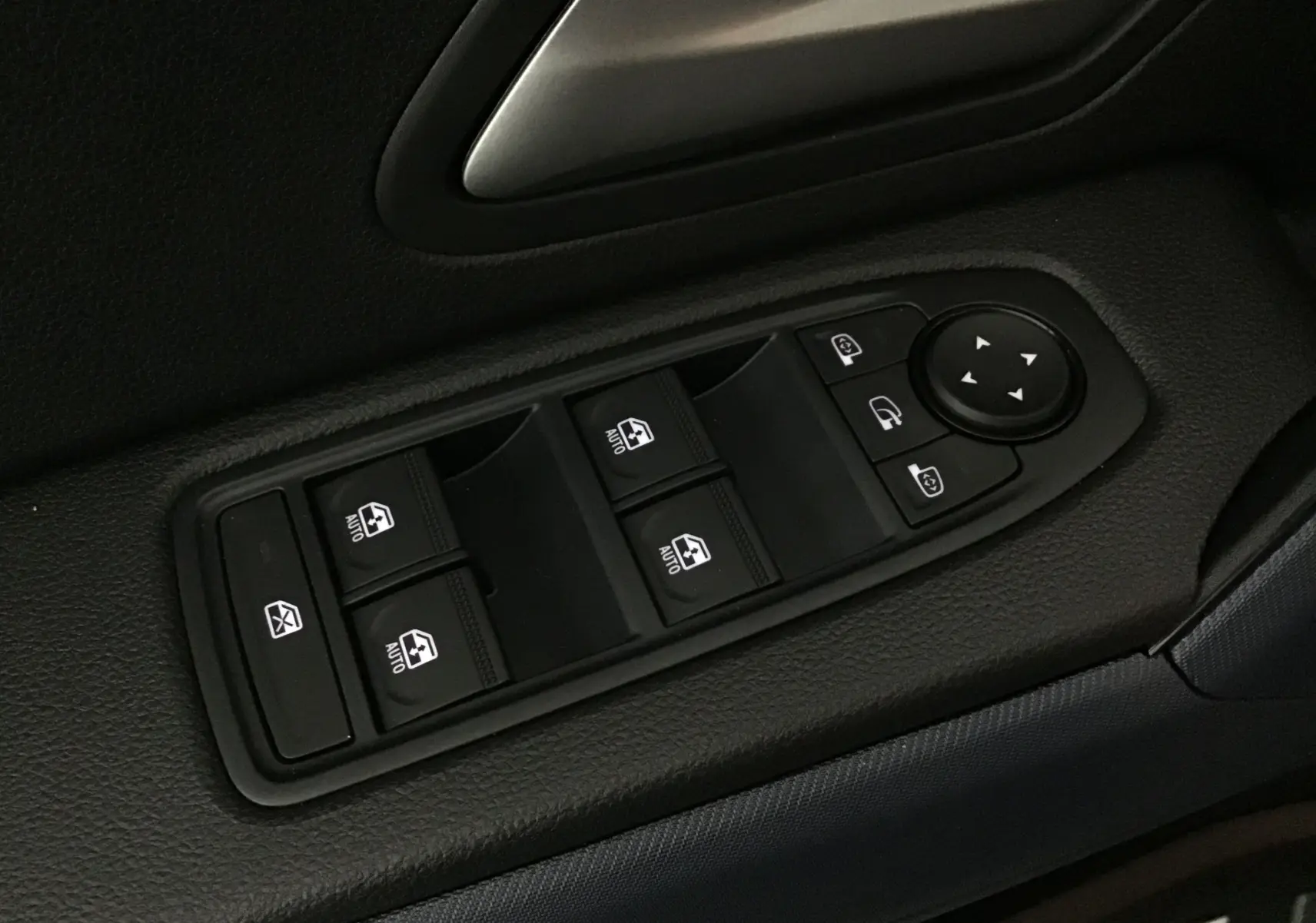Gros plan sur les commandes de lève-vitres et réglage des rétroviseurs côté conducteur du Dacia Duster 2025 kaki lichen.