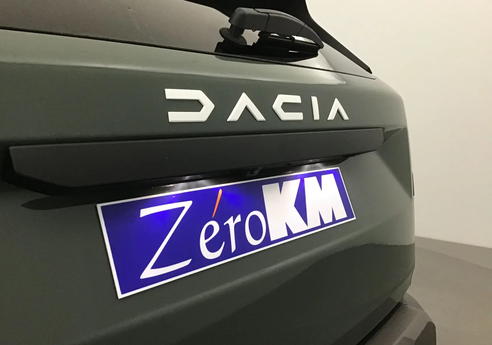Gros plan sur l'arrière kaki lichen du Dacia Duster 2025 avec logo DACIA et plaque Zéro KM visible.