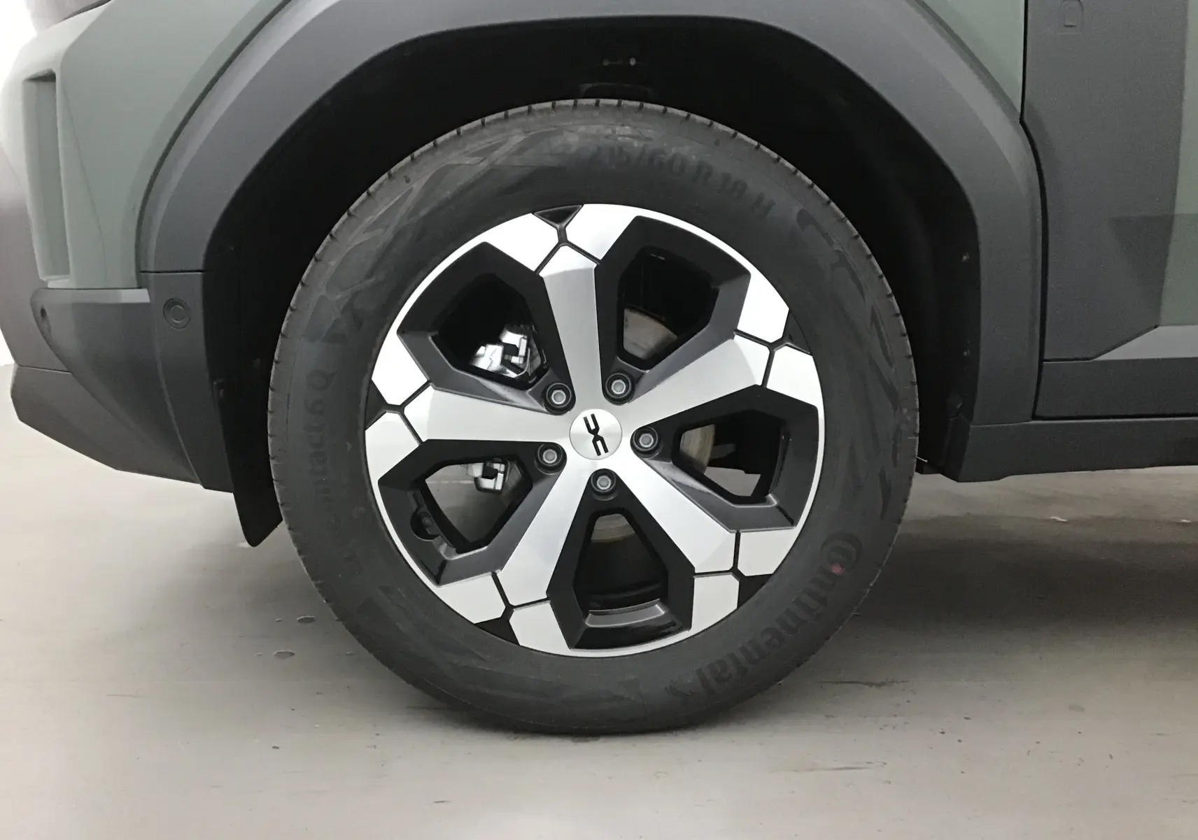 Gros plan sur la roue avant gauche du Dacia Duster 2025 kaki lichen, avec jante alliage au design géométrique noir et argent.