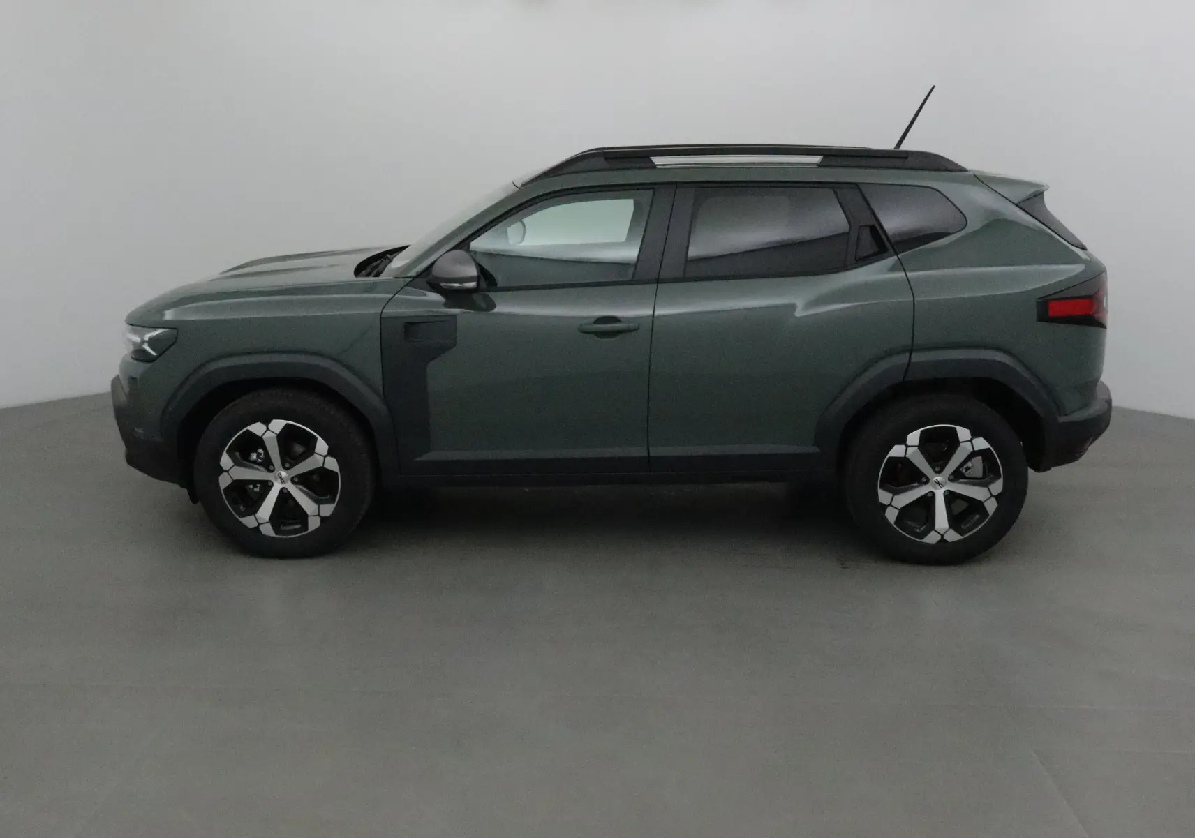 Profil côté gauche du Dacia Duster 2025 en kaki lichen, avec jantes alliage et toit noir contrasté.