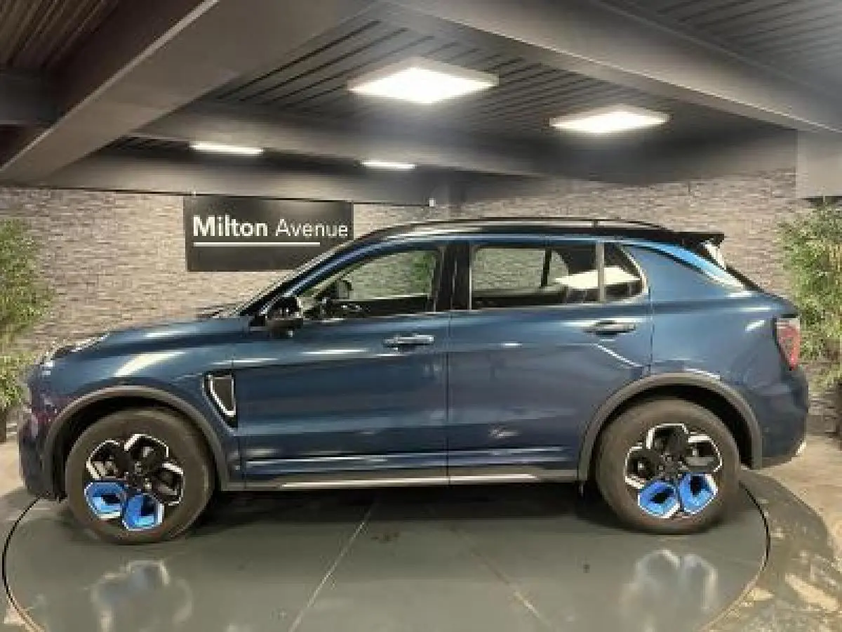 Profil côté gauche du SUV Lynk & Co 01 bleu métallisé avec jantes originales bicolores en showroom.