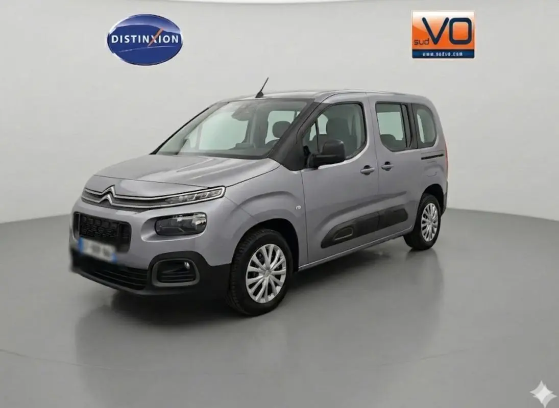 Citroën Berlingo gris clair en 3/4 avant droit, avec protections noires latérales et jantes alliage.