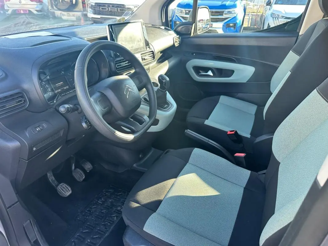 Vue intérieure côté conducteur du Citroën Berlingo gris clair 2020, montrant le volant, tableau de bord et sièges bi-ton.