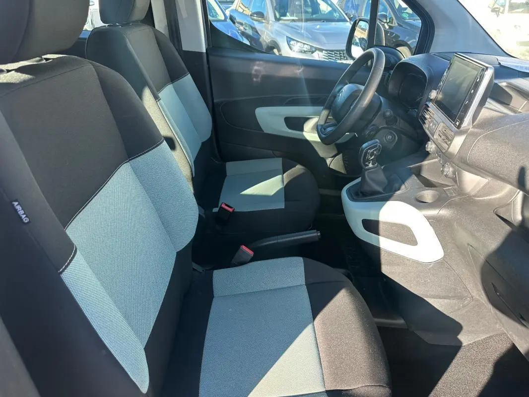 Vue intérieure côté gauche du Citroën Berlingo 2020, sièges bicolores noirs et gris, tableau de bord avec écran tactile.