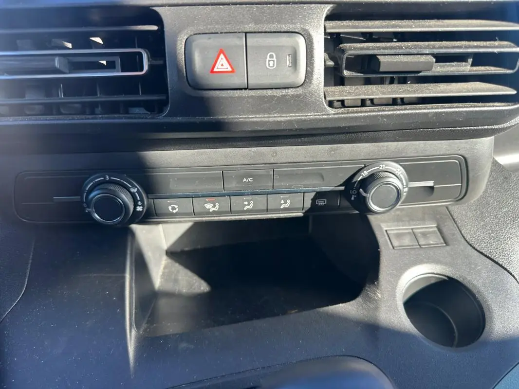 Vue rapprochée de la console centrale du Citroën Berlingo gris clair 2020, montrant les commandes de climatisation et les aérateurs.