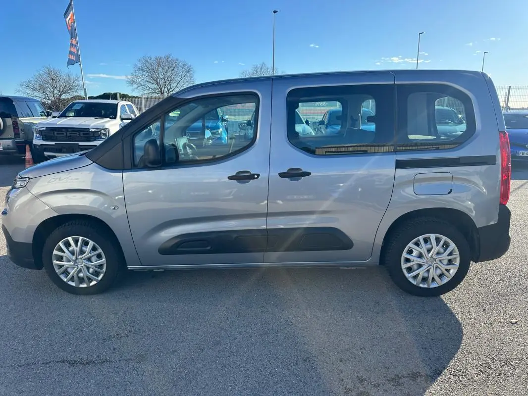Vue de profil côté gauche d'un Citroën Berlingo gris clair 2020 avec protections noires sur les portes et jantes alliage.