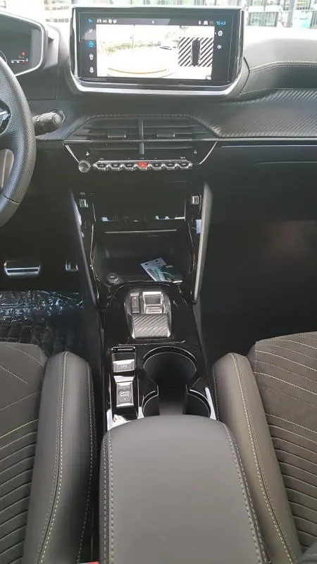 Vue intérieure centrée sur la console centrale et l'écran tactile du Peugeot 208 Hybrid 110 e-DCS6 GT, finition noire élégante.
