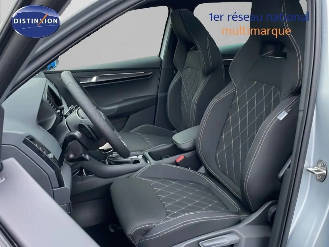 Vue intérieure côté conducteur du Skoda Karoq argent 2025, mettant en valeur les sièges sport noirs avec surpiqûres blanches.