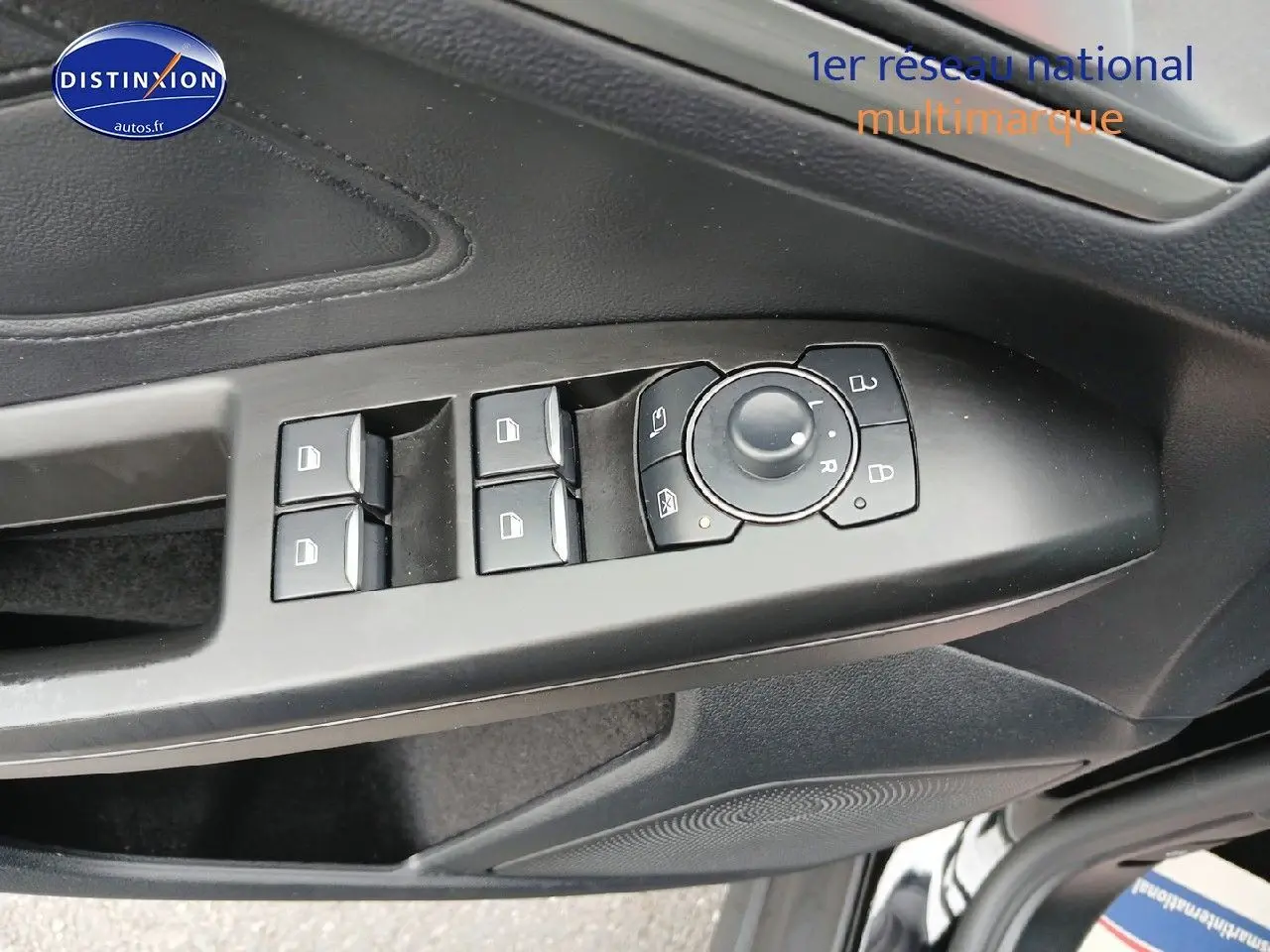 Gros plan sur la commande des vitres et rétroviseurs côté conducteur d'une Ford Focus noir Agate métallisé.