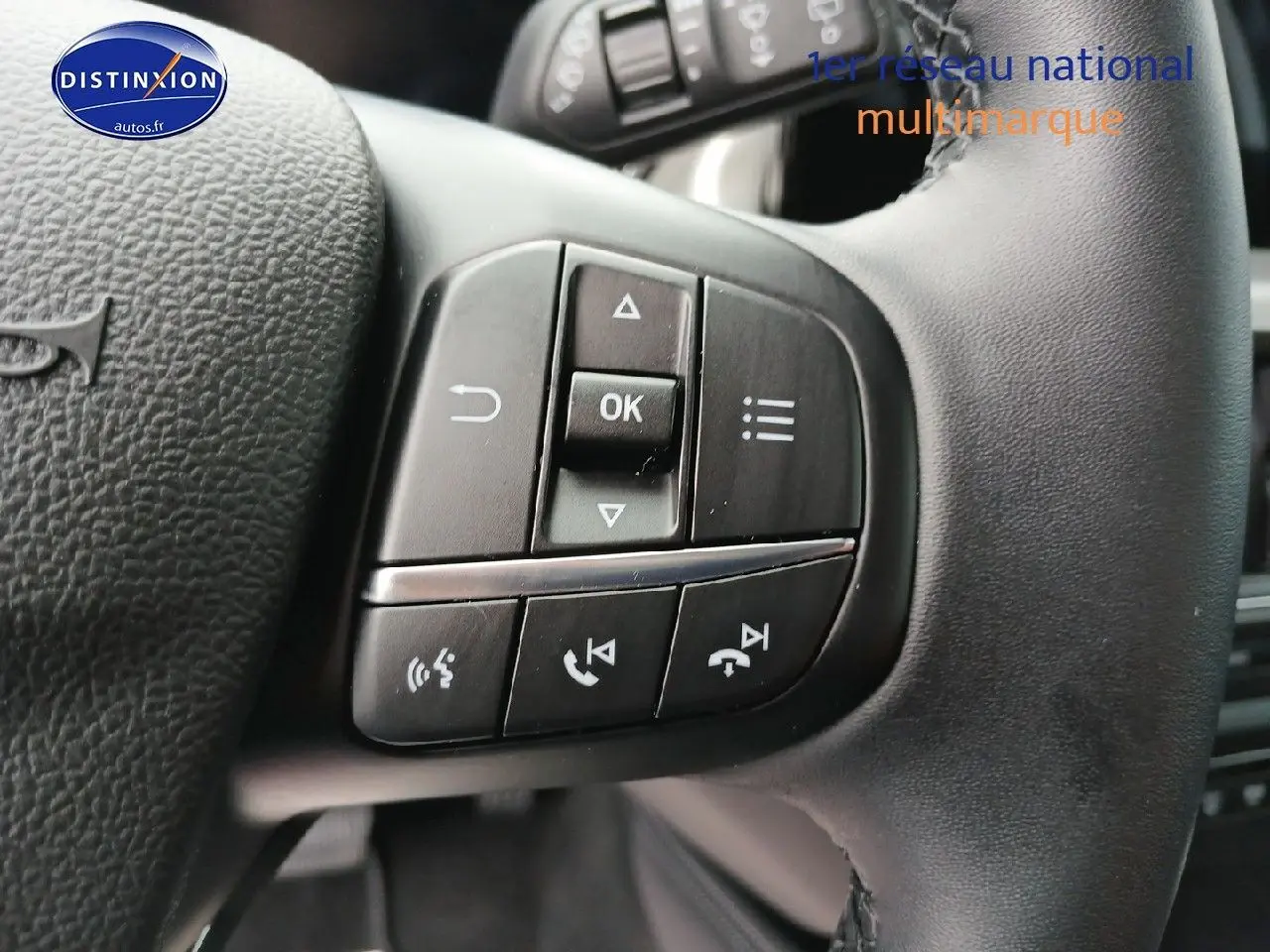 Gros plan sur les commandes multifonctions du volant cuir noir de la Ford Focus 2024 Titanium X Business.