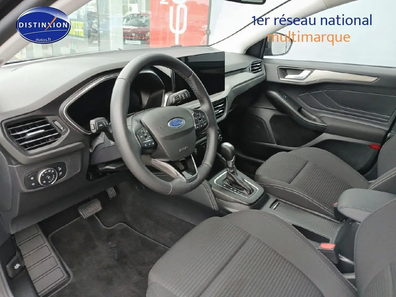 Vue intérieure côté conducteur de la Ford Focus 2024 noir Agate, volant cuir multifonction et console centrale visible.