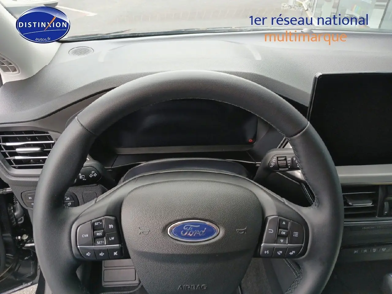Vue rapprochée du volant cuir noir multifonction de la Ford Focus 2024, tableau de bord et écran tactile visibles.