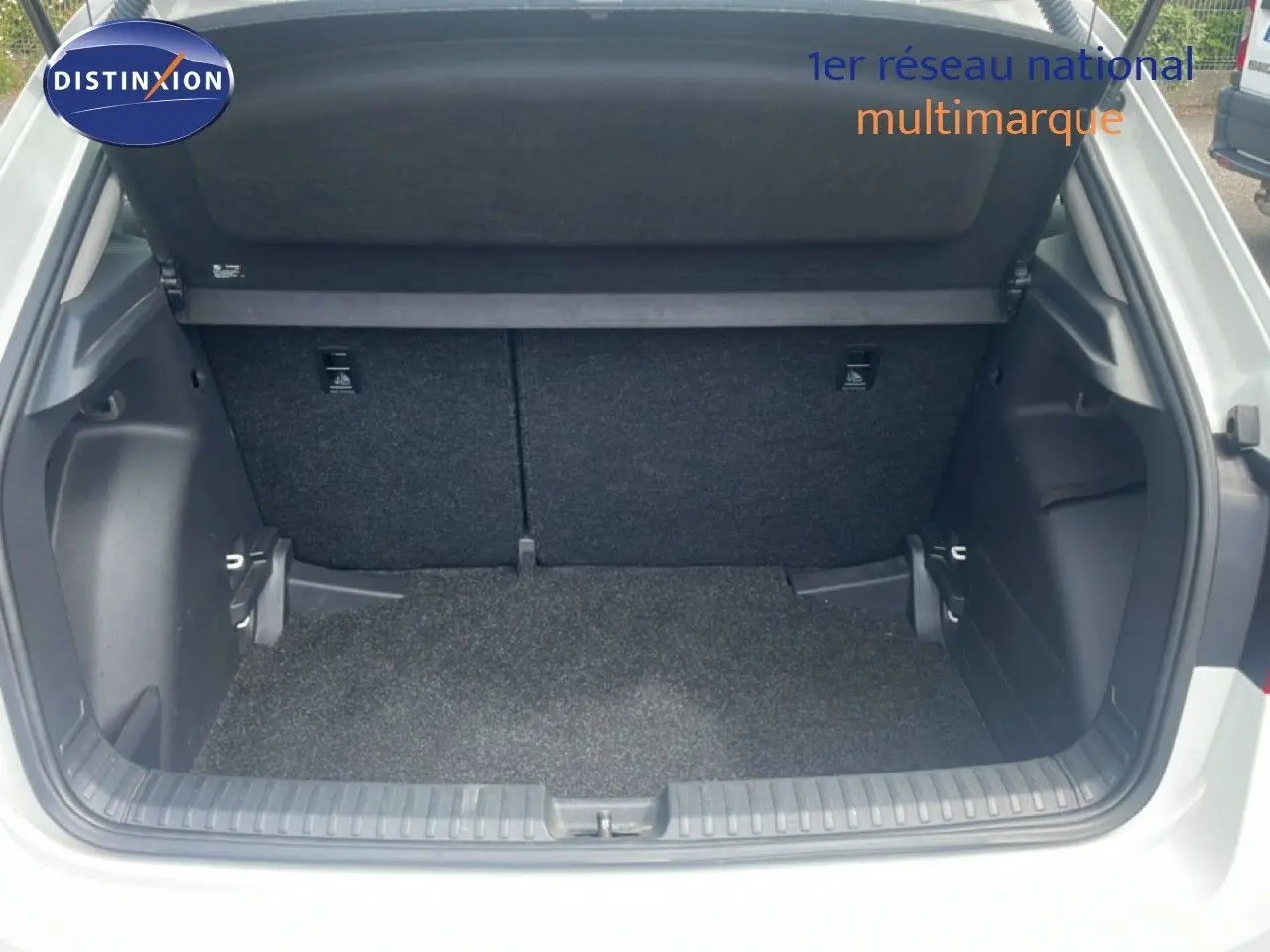 Coffre ouvert d’une Skoda Fabia blanc candy, vue arrière montrant l’espace de chargement vide et le cache-bagages relevé.