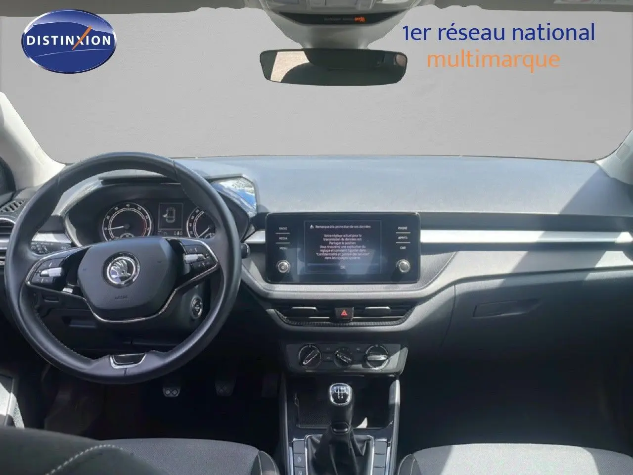 Intérieur de la Skoda Fabia 2022 blanc candy, vue frontale du tableau de bord avec volant cuir et écran tactile central.