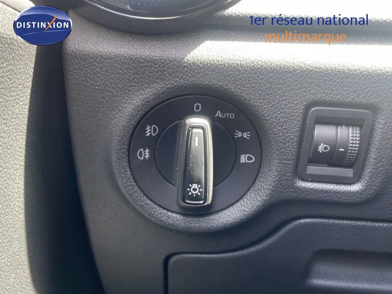 Gros plan sur le bouton de commande des phares d'une Skoda Fabia blanche, intérieur noir texturé visible.