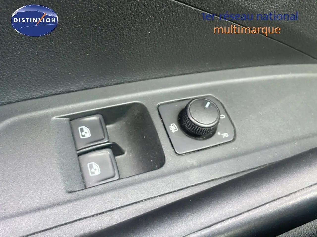 Gros plan sur les commandes de lève-vitres et réglage des rétroviseurs côté conducteur d'une Skoda Fabia blanche.