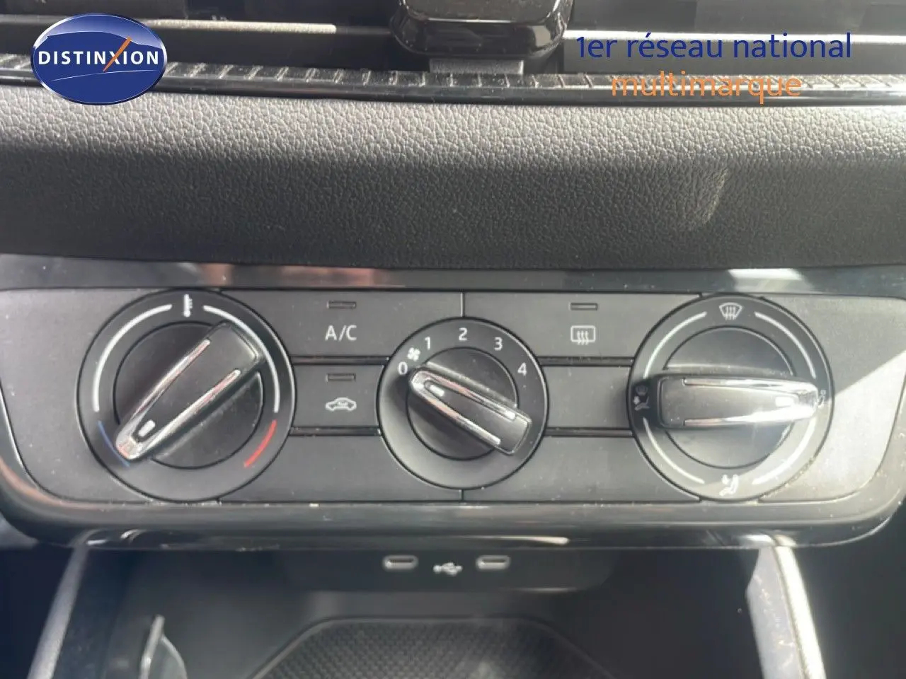 Vue rapprochée des commandes de climatisation manuelle sur tableau de bord noir d'une Skoda Fabia blanche.