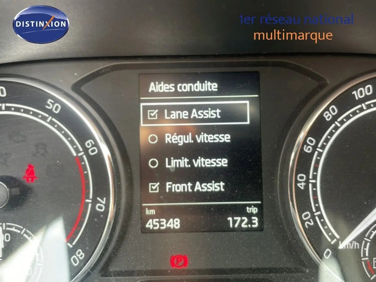 Tableau de bord de Skoda Fabia blanc Candy 2022 montrant l'écran des aides à la conduite et le compteur kilométrique.