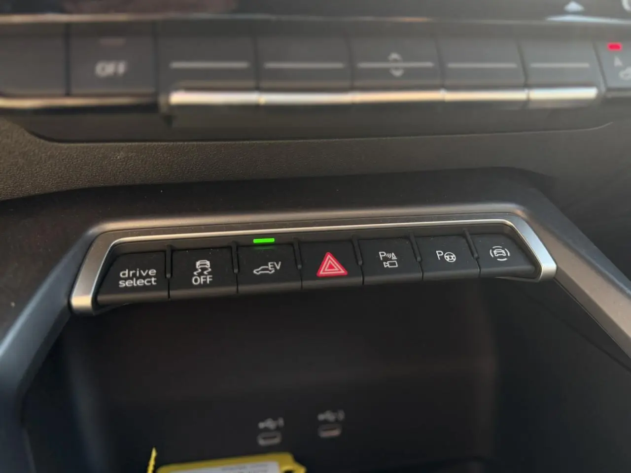 Gros plan sur la rangée de boutons de commande noirs avec éclairage, dans l’habitacle de l’Audi A3 Sportback noir Mythe.