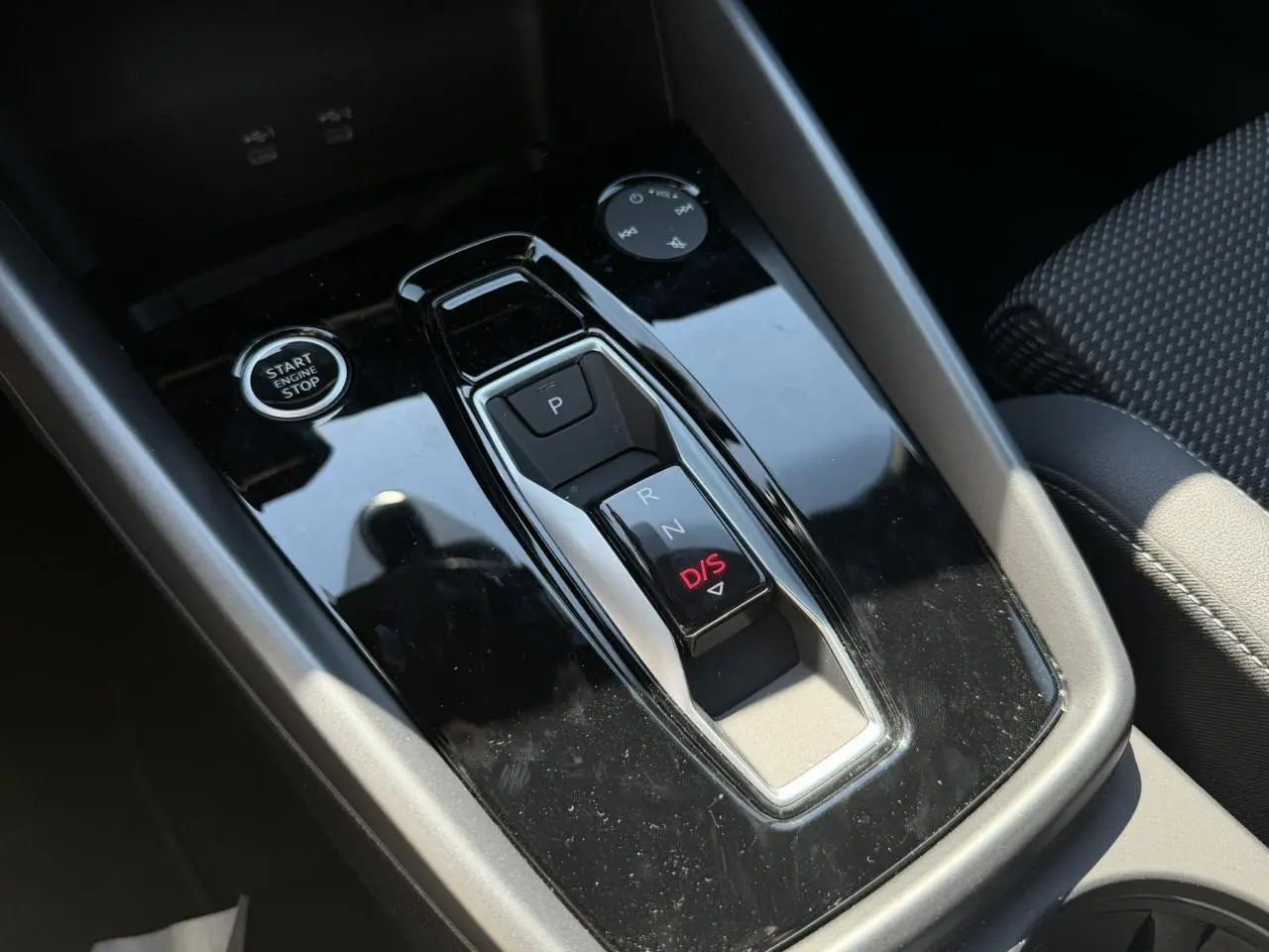 Vue rapprochée de la console centrale noire brillante avec sélecteur de boîte auto et bouton Start/Stop de l'Audi A3 Sportback.