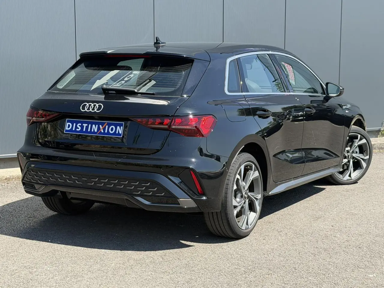 Audi A3 Sportback noir Mythe vue 3/4 arrière droit, jantes alliage 5 branches en Y gris brillant et feux LED dynamiques.