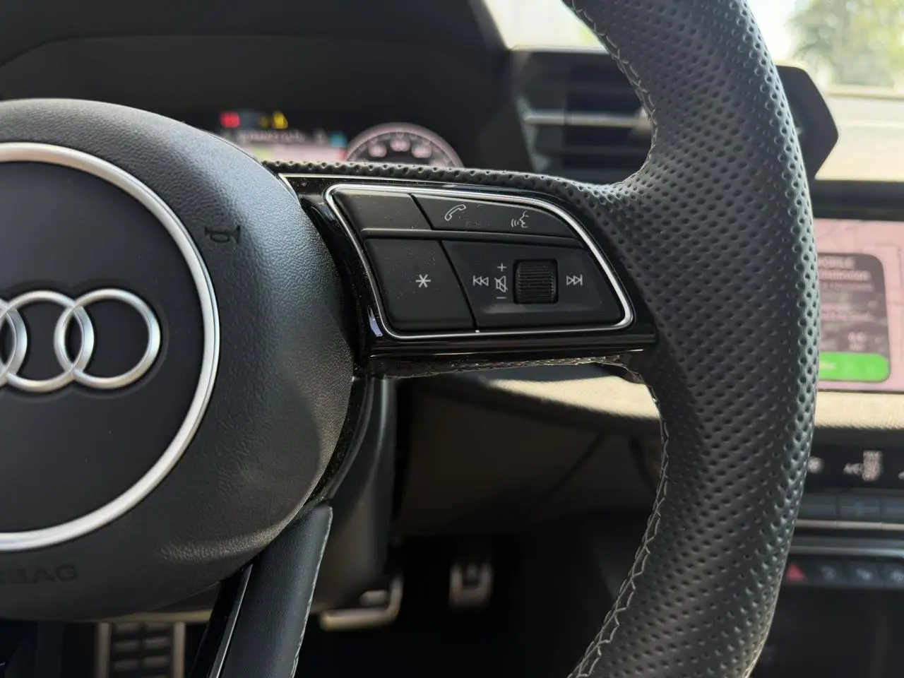 Gros plan sur le volant cuir perforé noir de l'Audi A3 Sportback 2025 avec commandes multifonctions sur le côté droit.