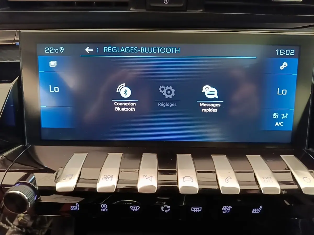 Gros plan sur l’écran tactile central et les commandes piano argentées du tableau de bord de la Peugeot 508 gris foncé.