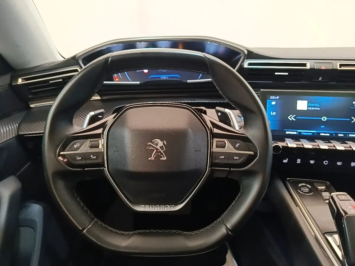 Vue rapprochée du volant cuir noir de la Peugeot 508 avec tableau de bord digital et écran tactile central.
