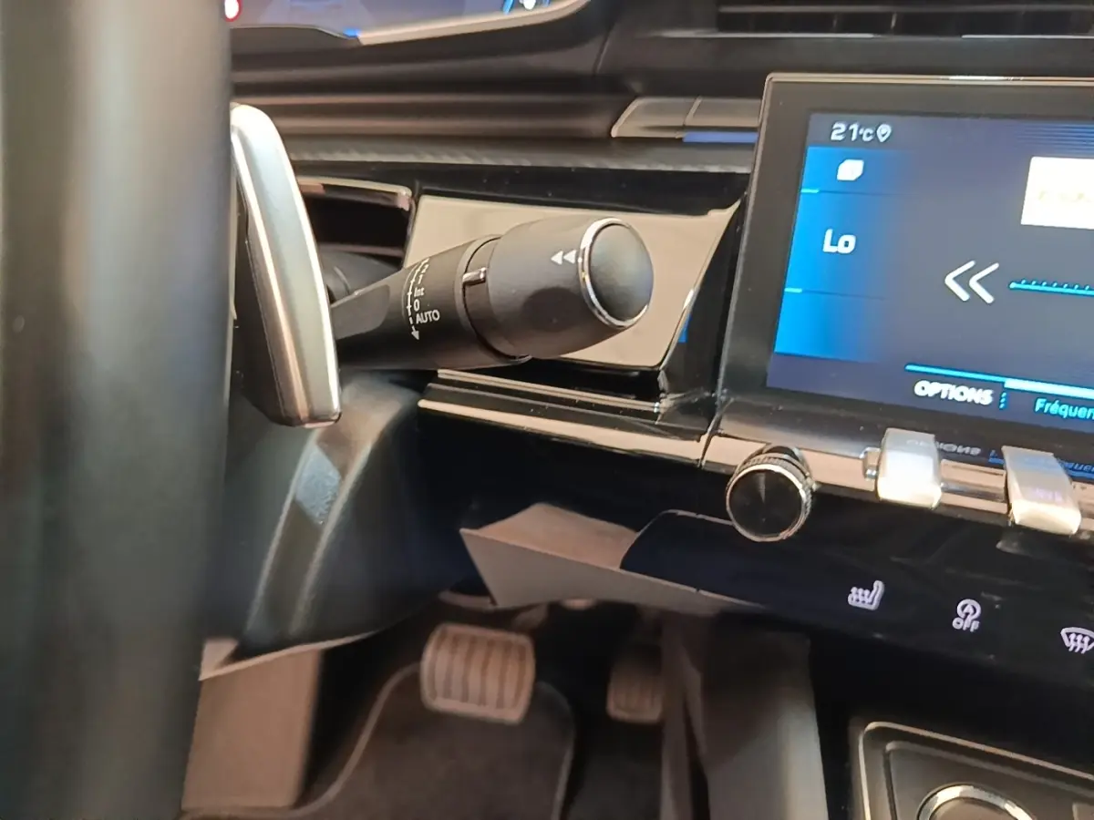 Gros plan intérieur sur la commande de clignotant et l’écran tactile du tableau de bord noir de la Peugeot 508 gris foncé.