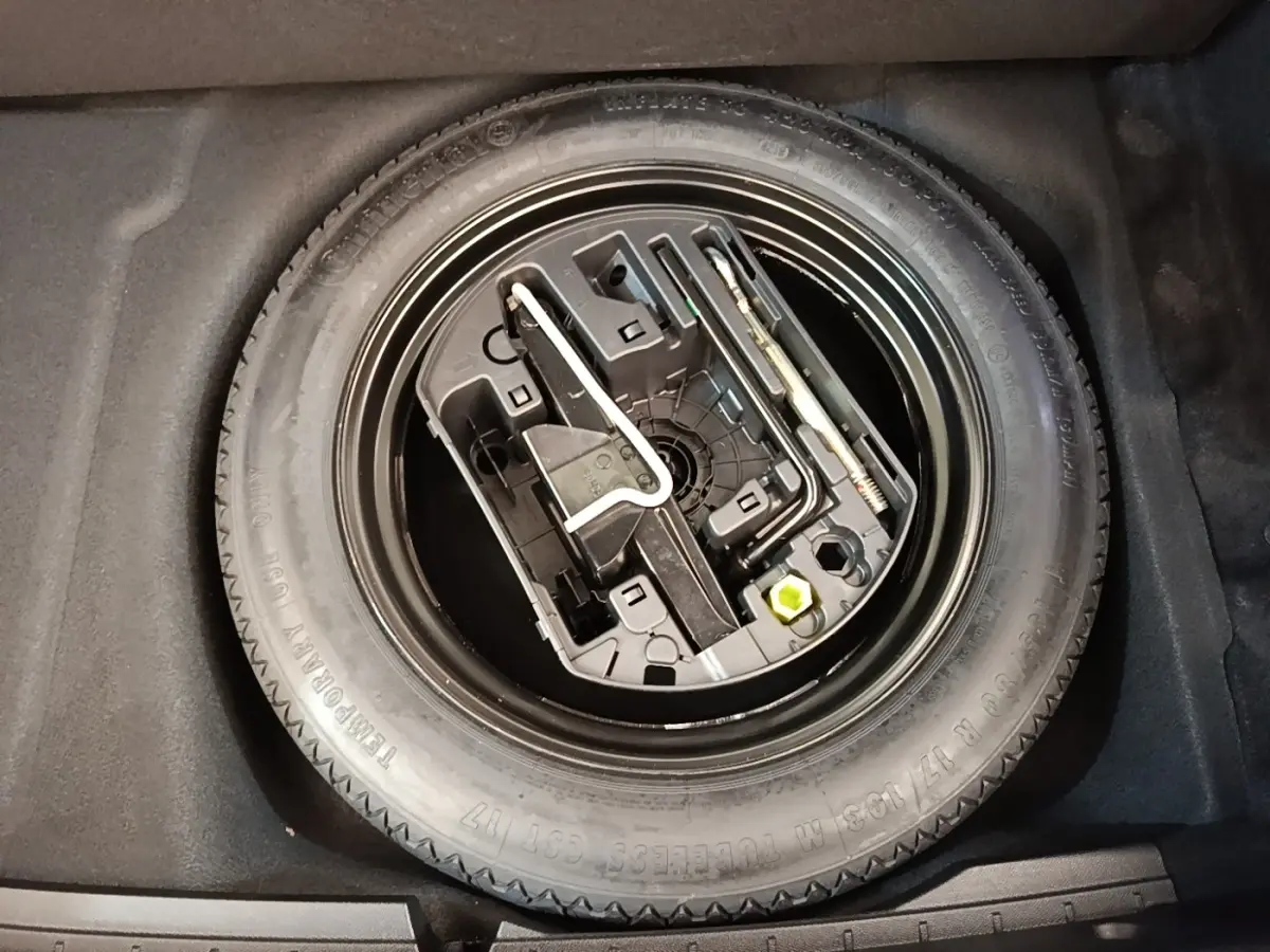 Roue de secours avec kit d'outils intégrés dans le coffre d'une Peugeot 508 gris foncé, vue de dessus.